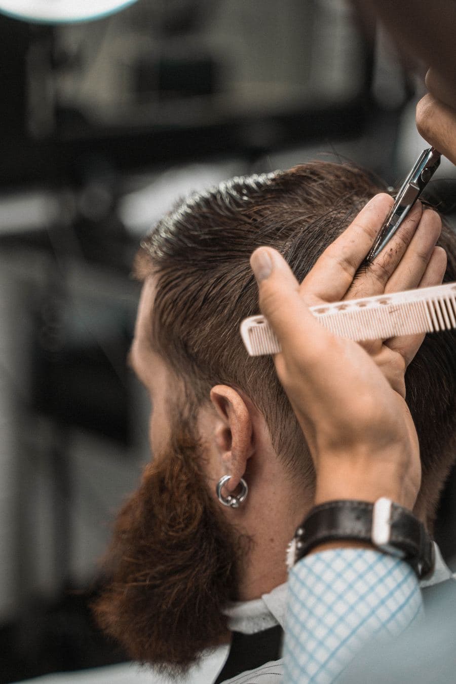 Barbeiro acertando o corte com pente e tesoura